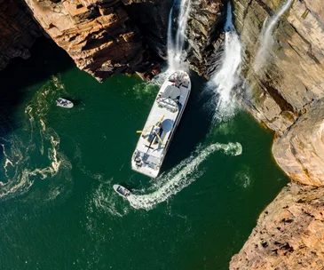 The Kimberley cruises ship True North in the Kimberley WA. Photo of the Kimberley cruise ship at the base of a waterfall