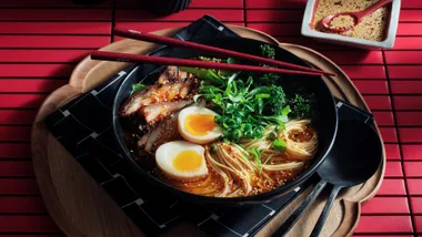bowl of ramen with noodles chicken and egg in a black bowl on a red table to represent the best japanese recipes