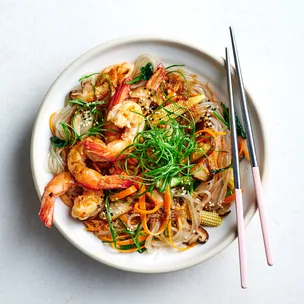 Japchae with prawns in white bowl with chopsticks.