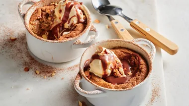 Two chocolate puddings topped with ice cream and dusted with chocolate powder