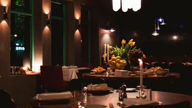 The dining room of new Melbourne restaurant Roma, with a candle-lit atmosphere and a table of flowers and produce.